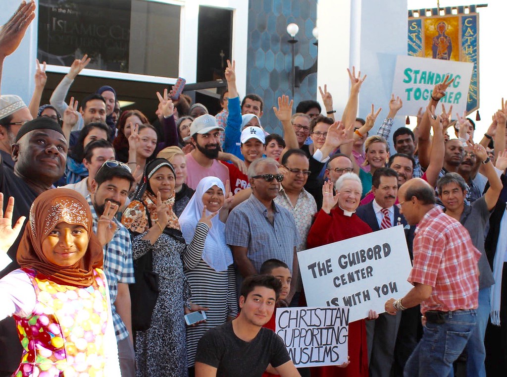 Christians supporting Muslims outside of building with signs that say "Stop the Hate"