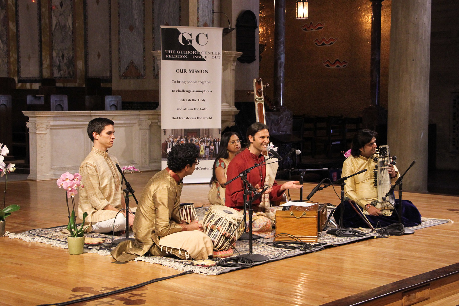 Group sitting on the floor smiling and holding intruments